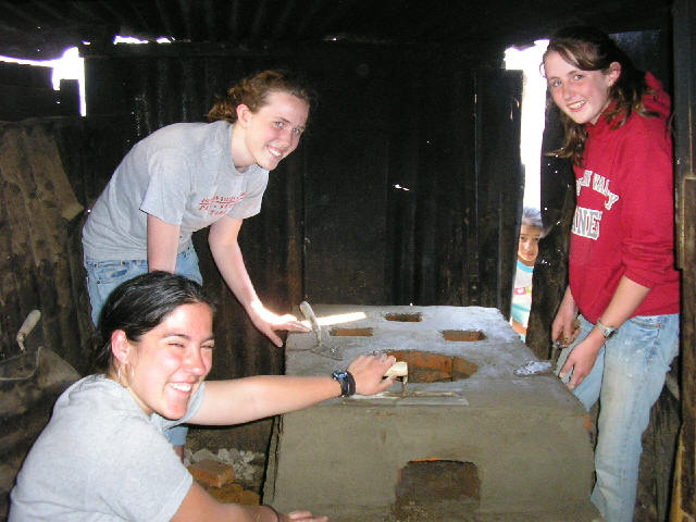 Spanish language students helping poor families in the construction of economic stoves